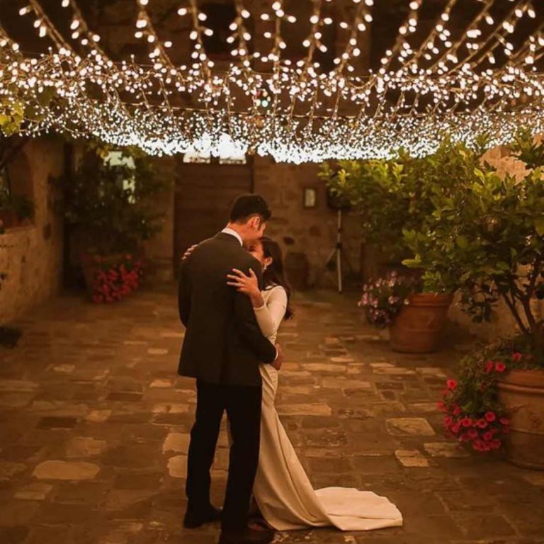 Wedding couple dances underneath fairy light sky