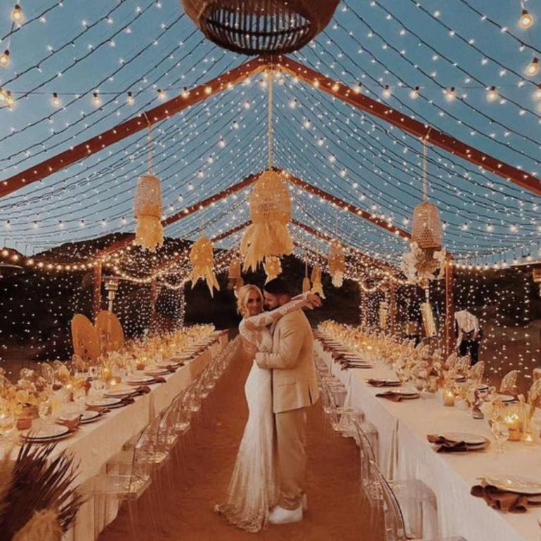 Couple standing under marquee of festoons