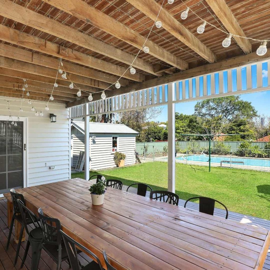 beautiful backyard with table and chairs and festoon lights hanging above dining area